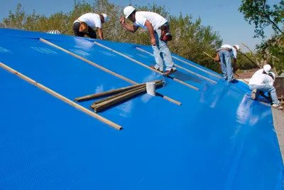 Emergency Roofing Services putting a tarp on a roof repair.